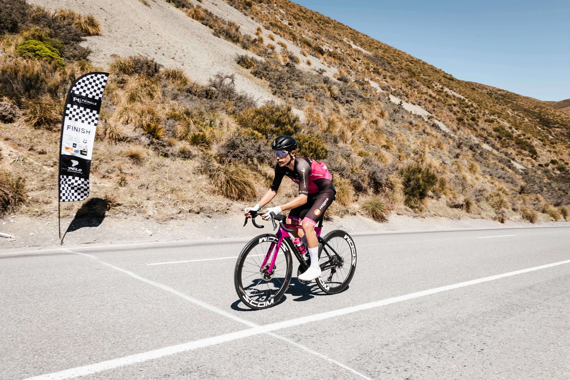 A Main Divide rider at the summit finish beside the race finish flag